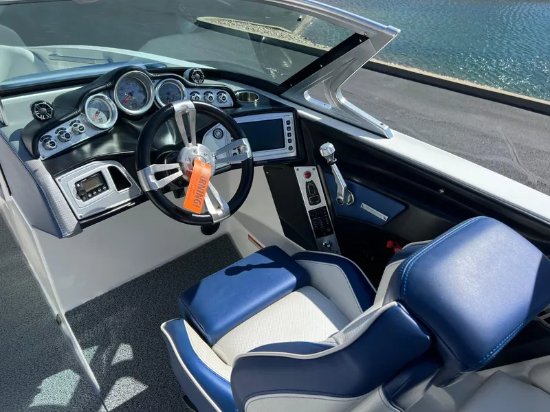 Slide: The Image of 2016 MasterCraft X23 boat cockpit with steering wheel, gauges, and blue seating. - 8
