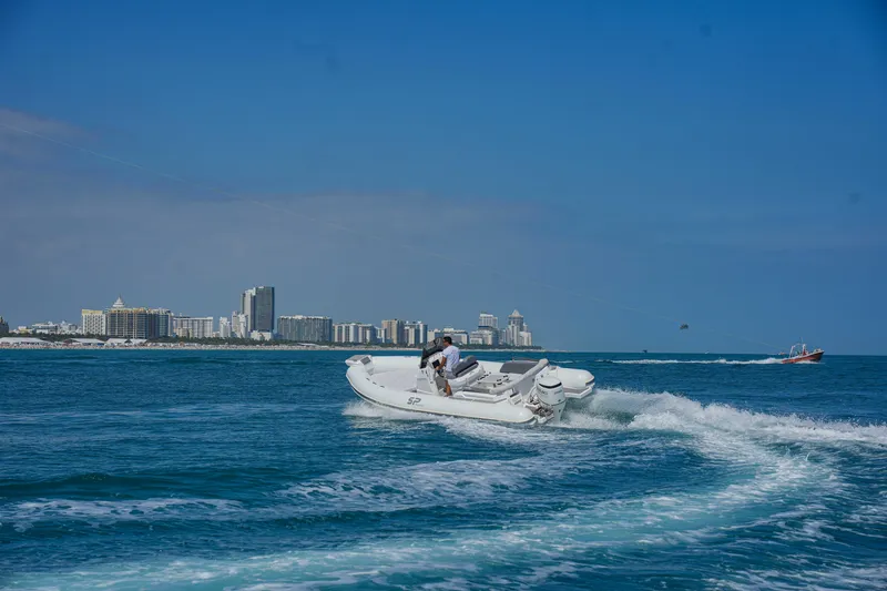 Slide: The Image of Sea Prop COMFORT 24 boat cruising on blue ocean near city skyline, 2025 model. - 3