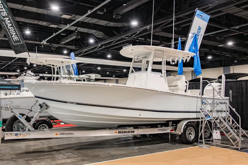 The Image of 2025 Regulator 26XO boat displayed indoors on a trailer at a marine exhibition. - 0