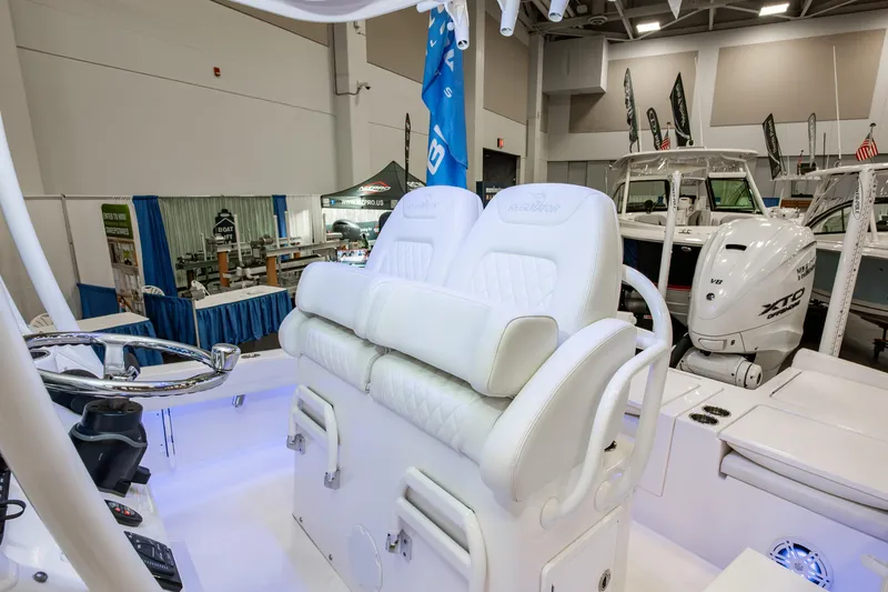 Slide: The Image of 2025 Regulator 26XO boat interior with white seating and steering wheel at a boat show. - 10