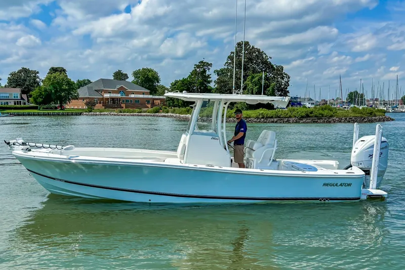 Slide: The Image of 2025 Regulator 26XO boat on calm water, with scenic shoreline background. - 21