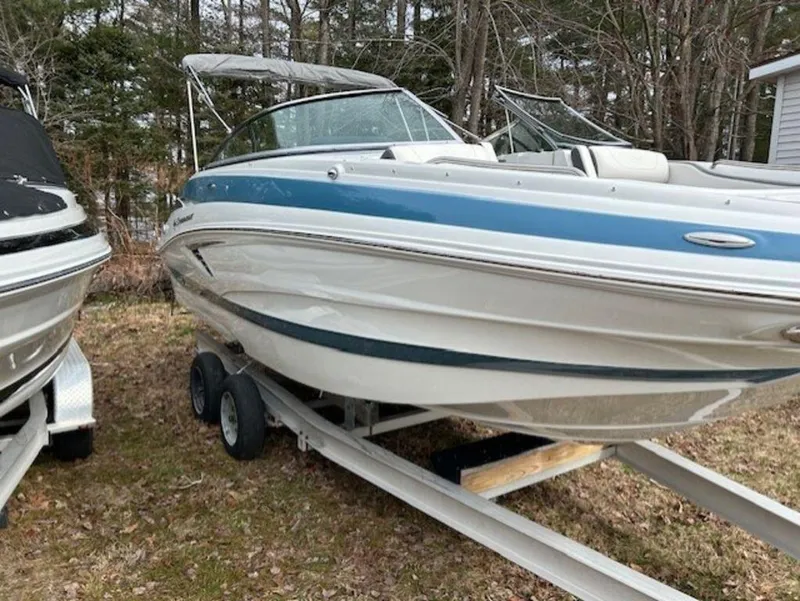 Slide: The Image of 2024 Crownline E Series E235 boat on a trailer in a wooded area. - 6