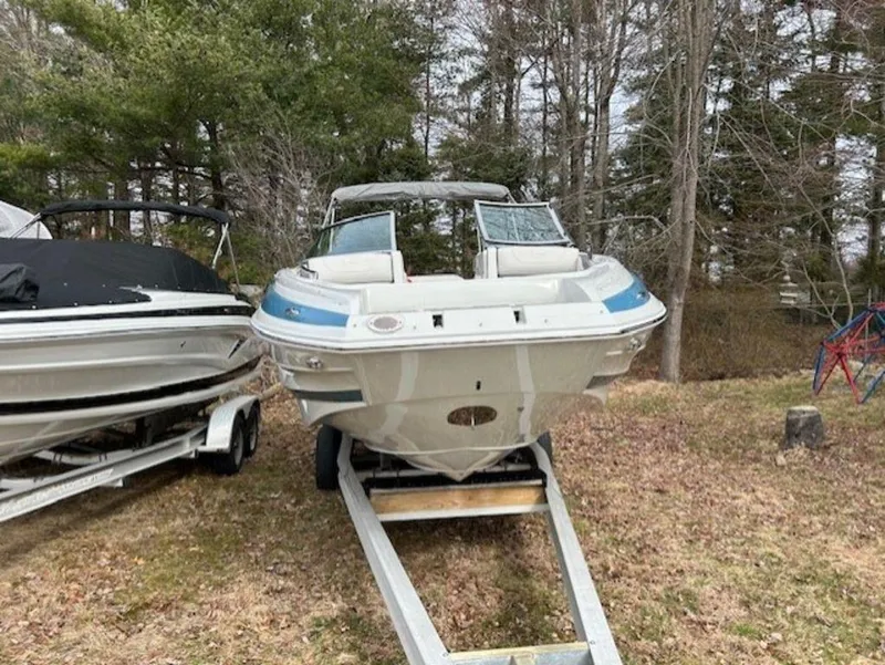 Slide: The Image of 2024 Crownline E Series E235 boat on a trailer in a wooded area. - 7