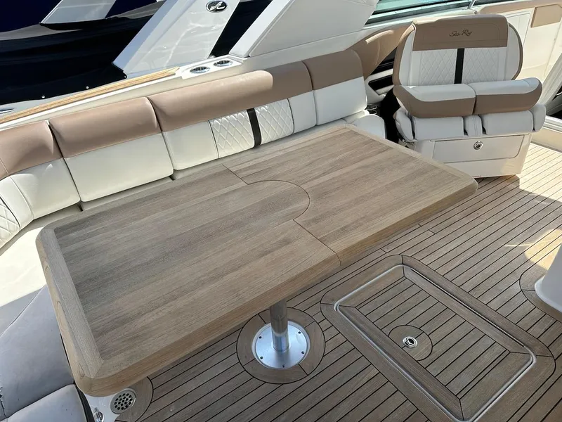 Slide: The Image of 2018 Sea Ray SLX 400 boat interior with wooden table and cushioned seating. - 11
