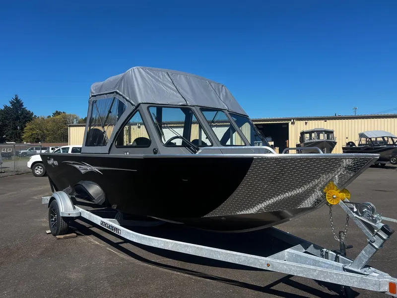 Slide: The Image of 2024 Fish Rite 200 Sportsman boat on trailer, black with canopy, parked outdoors. - 2