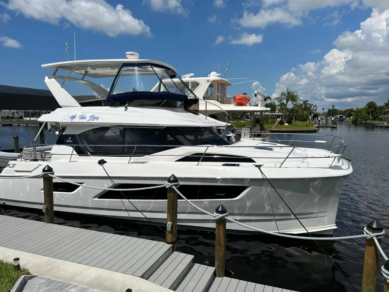 The Image of Aquila 44 Yacht 2020 docked by a serene waterfront under a blue sky. - 0