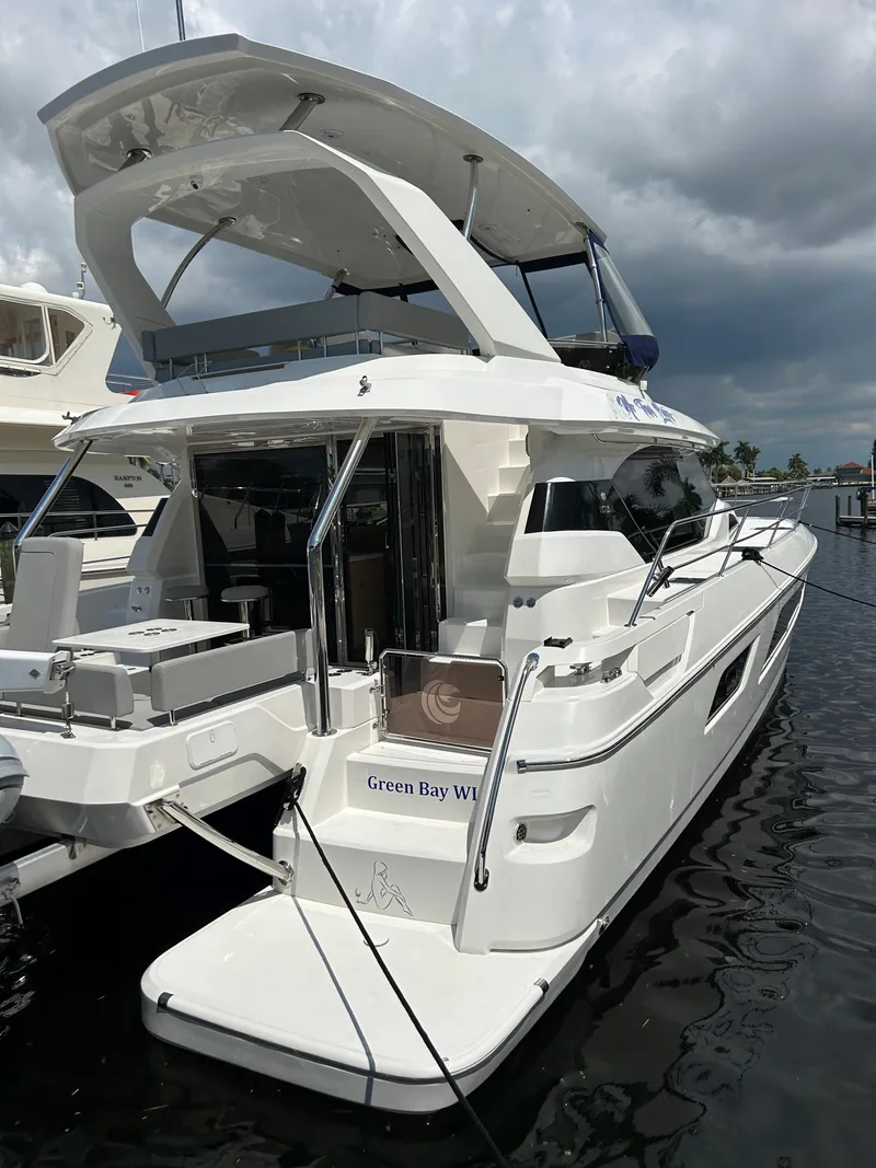 Slide: The Image of 2020 Aquila 44 Yacht docked, showcasing sleek design and spacious deck under cloudy skies. - 4