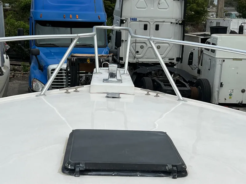 Slide: The Image of Bow view of 2000 Stuart Angler 32 Center Console boat, parked near trucks. - 33