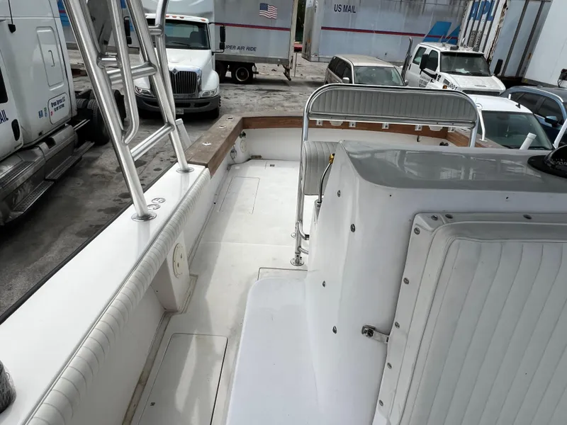 Slide: The Image of 2000 Stuart Angler 32 Center Console boat interior with seating and railing, parked near trucks. - 38