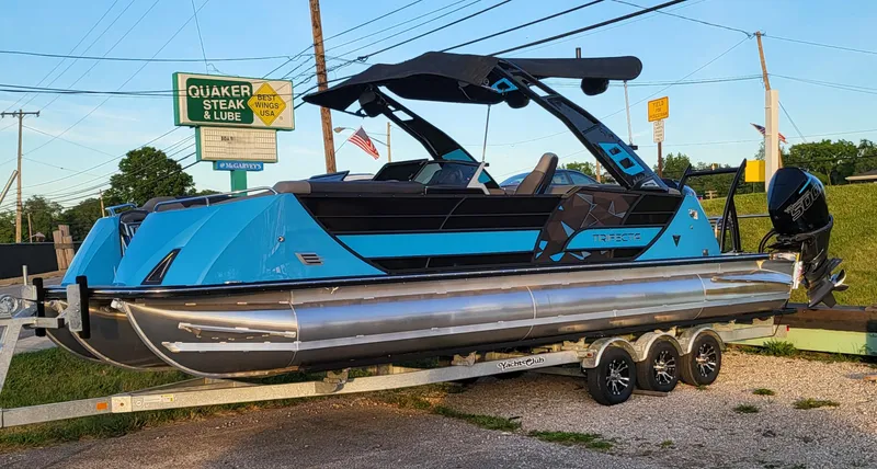 Slide: The Image of 2025 Trifecta 25 Sport RF9 DC 3.0+ pontoon boat on trailer in parking lot. - 3
