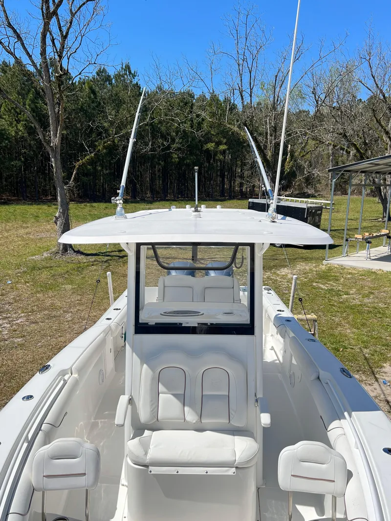 Slide: The Image of 2018 Sea Hunt Gamefish 30 boat with seating, antennas, and console, set against a wooded background. - 10