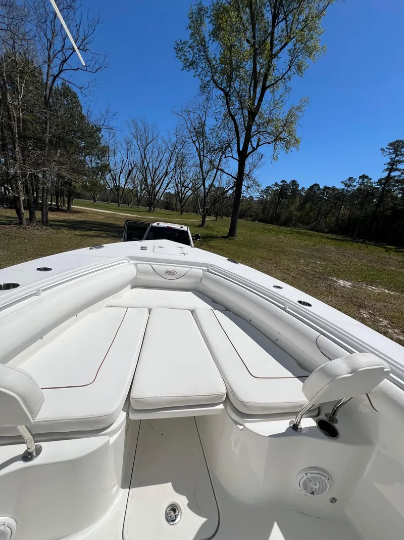 Slide: The Image of 2018 Sea Hunt Gamefish 30 boat on trailer, surrounded by trees and clear blue sky. - 6