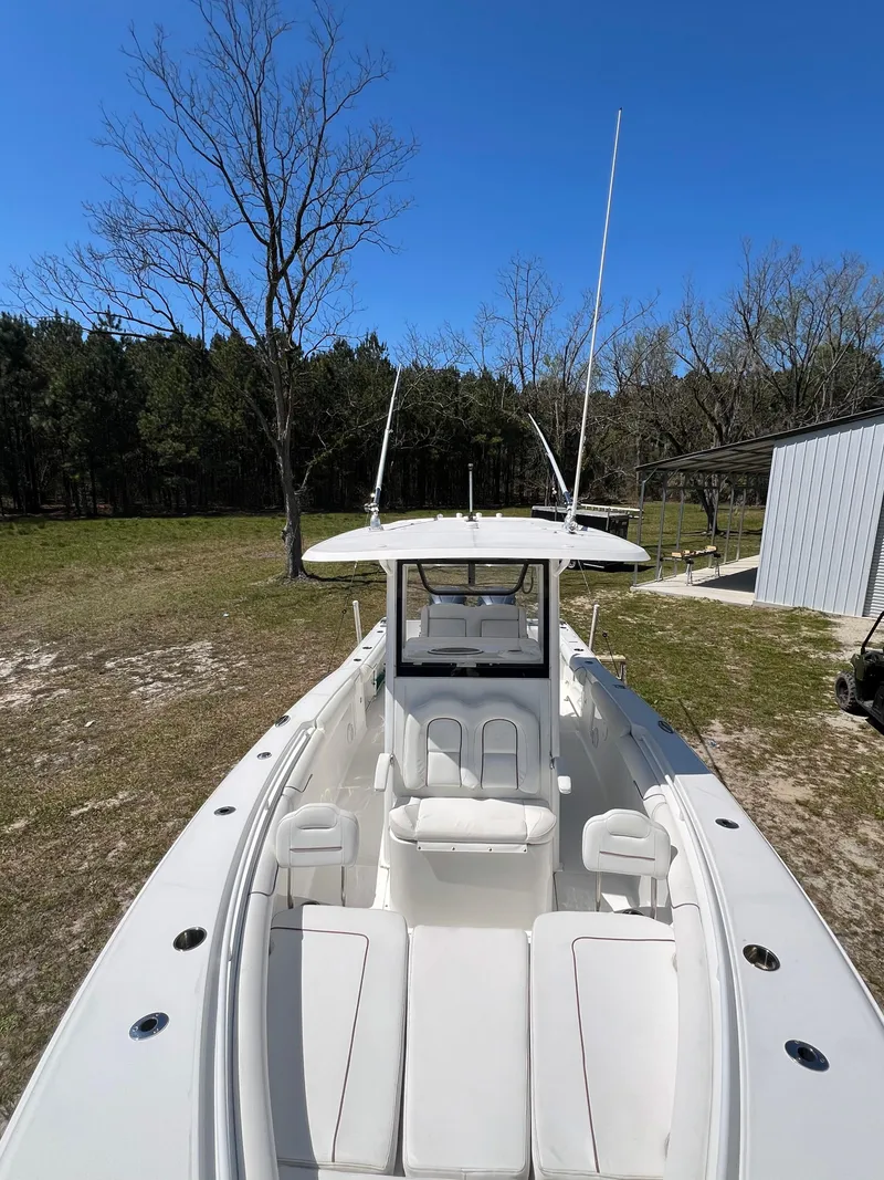 Slide: The Image of 2018 Sea Hunt Gamefish 30 boat on land, surrounded by trees and clear blue sky. - 9