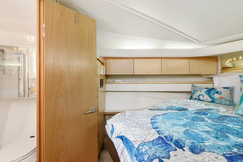 Slide: The Image of 1999 Tiara Yachts 4000 Express cabin with bed, wooden cabinets, and bathroom. - 7