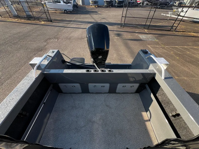 Slide: The Image of 2024 Fish Rite 180 Sportsman boat interior with motor, docked outdoors. - 8