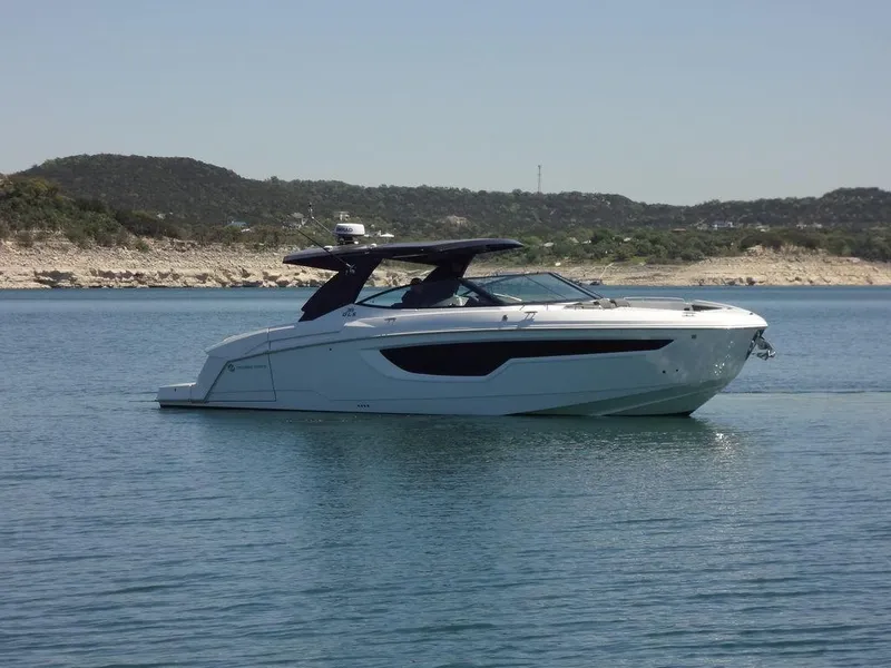 Slide: The Image of 2021 Cruisers Yachts 38 GLS I/O on a serene lake with scenic hills in the background. - 13
