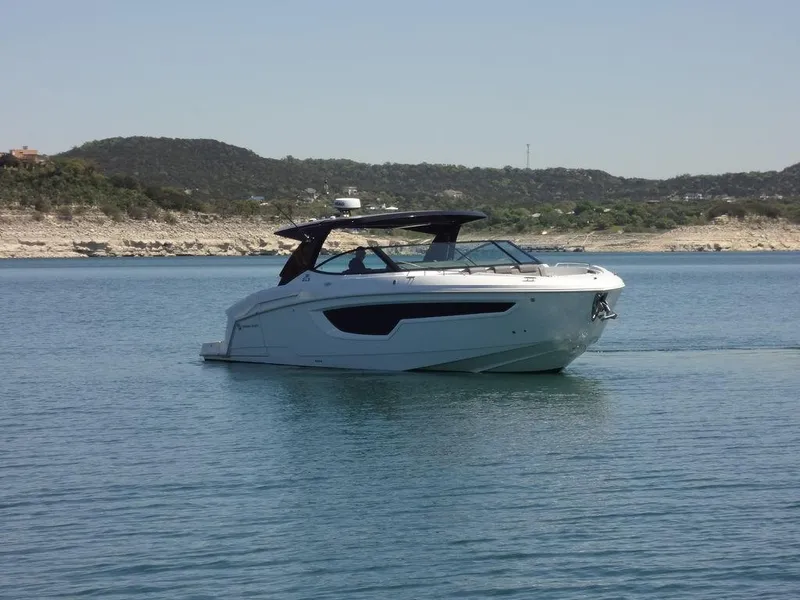 Slide: The Image of 2021 Cruisers Yachts 38 GLS I/O on a serene lake with scenic hills in the background. - 14