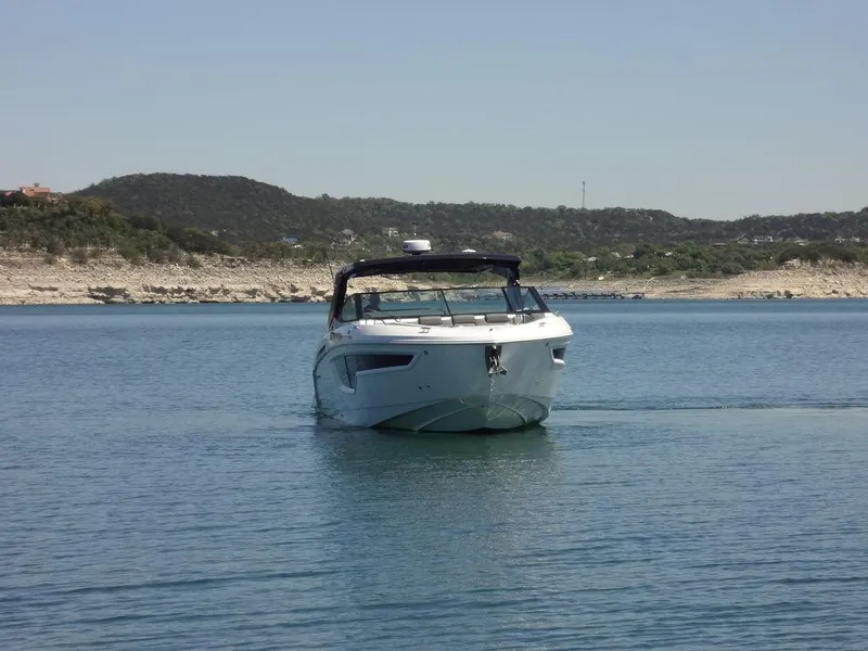 Slide: The Image of 2021 Cruisers Yachts 38 GLS I/O on a calm lake with scenic hills in the background. - 16