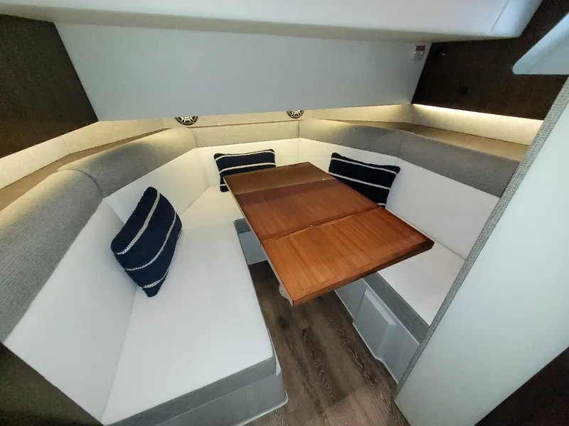 Slide: The Image of 2021 Cruisers Yachts 38 GLS I/O cabin with cozy seating and wooden table. - 19