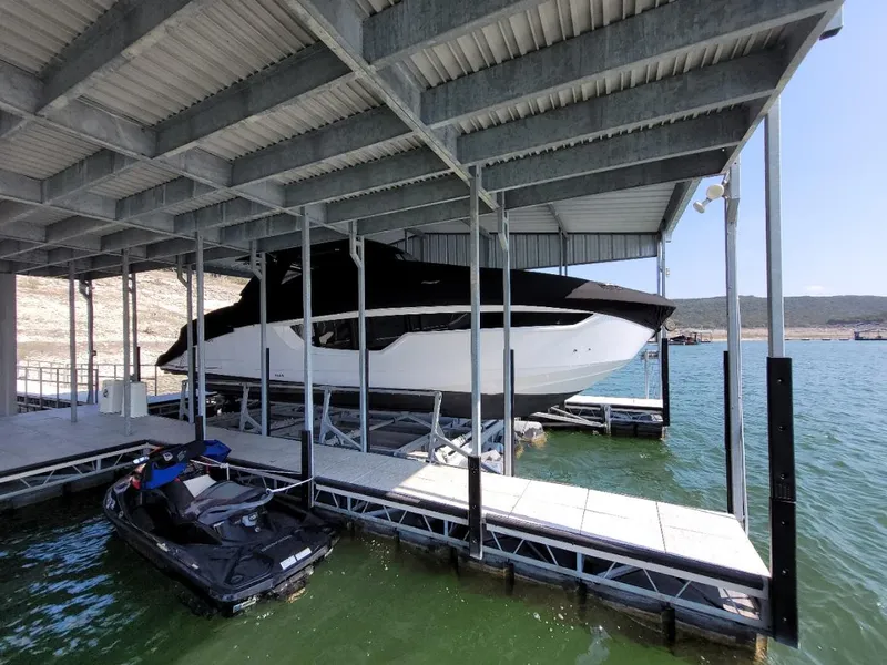 Slide: The Image of 2021 Cruisers Yachts 38 GLS I/O docked under a covered marina with a jet ski nearby. - 29