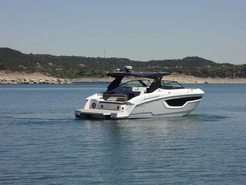 Slide: The Image of 2021 Cruisers Yachts 38 GLS I/O on a serene lake with scenic hills in the background. - 9