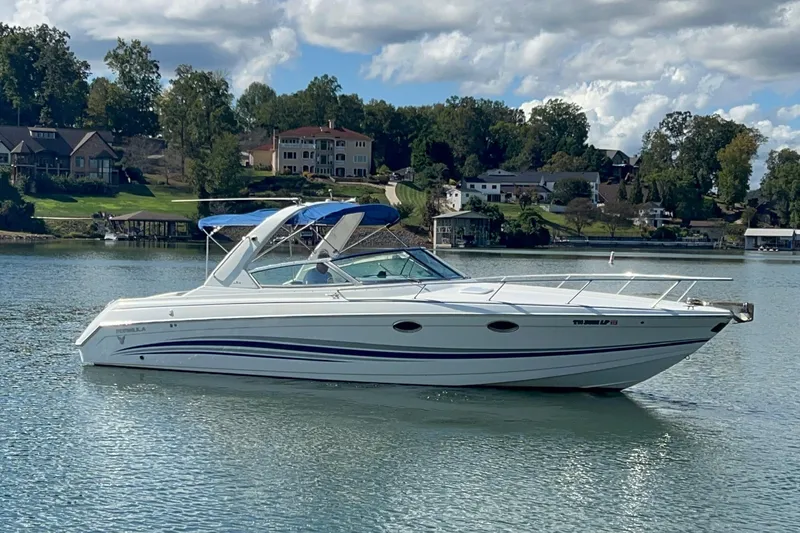 Slide: The Image of 2004 Formula 330 Sun Sport boat on a serene lake with houses in the background. - 100