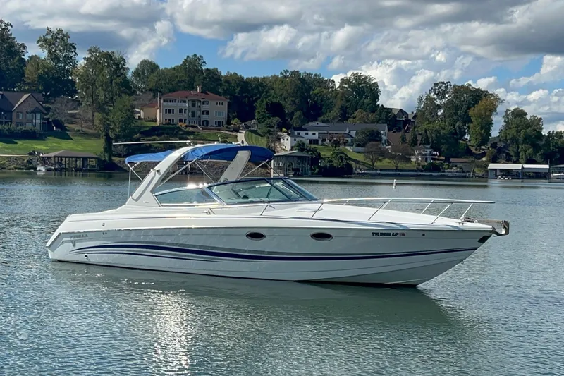 Slide: The Image of 2004 Formula 330 Sun Sport boat on a serene lake with houses in the background. - 102