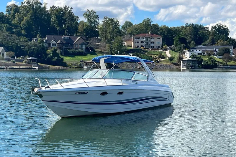 Slide: The Image of 2004 Formula 330 Sun Sport boat on a serene lake with houses in the background. - 108