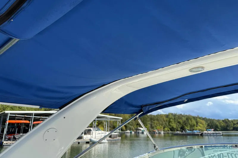 Slide: The Image of 2004 Formula 330 Sun Sport boat with blue canopy, docked near a marina. - 70