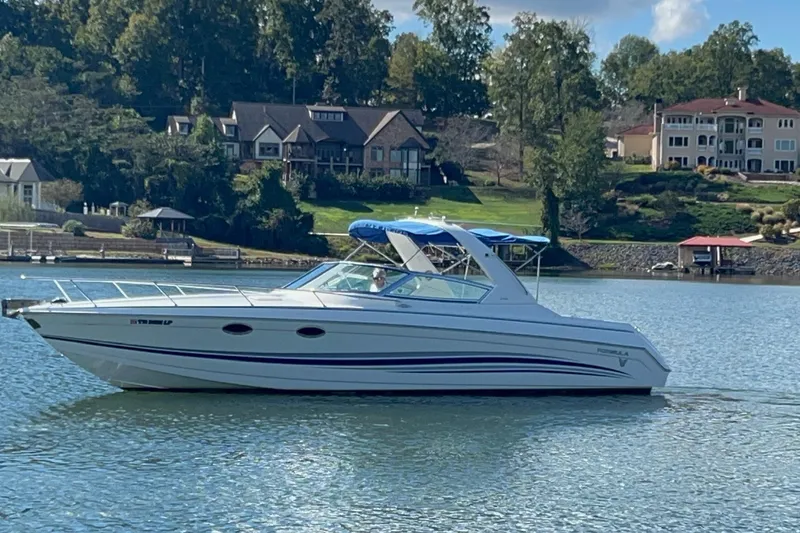 Slide: The Image of 2004 Formula 330 Sun Sport boat cruising on a scenic lake with waterfront homes. - 80