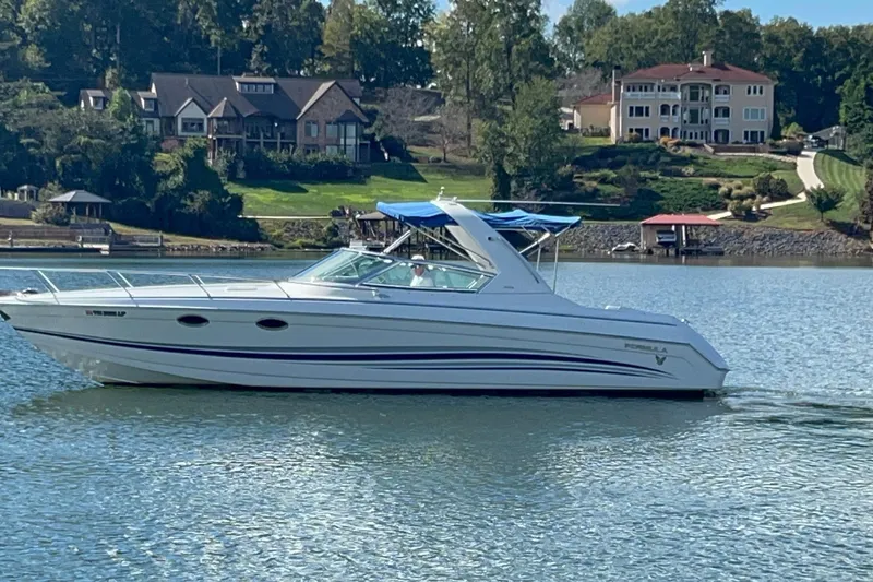 Slide: The Image of 2004 Formula 330 Sun Sport boat cruising on a lake with luxury homes in the background. - 82