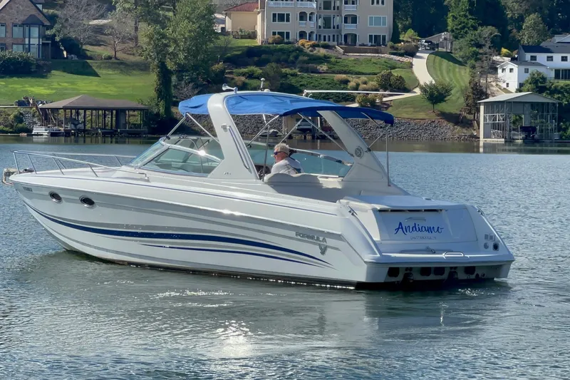 Slide: The Image of 2004 Formula 330 Sun Sport boat cruising on a scenic lake with waterfront homes. - 84