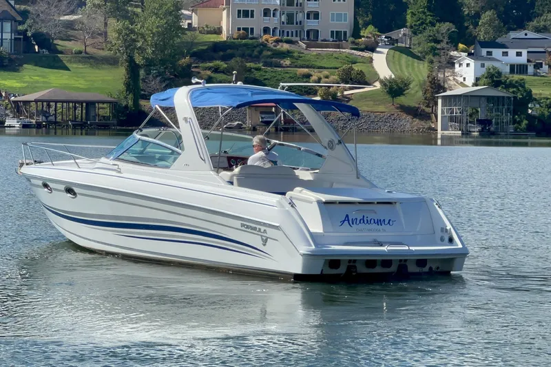 Slide: The Image of 2004 Formula 330 Sun Sport boat cruising on a serene lake with scenic background. - 85