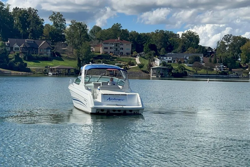 Slide: The Image of 2004 Formula 330 Sun Sport boat on a serene lake with houses in the background. - 90