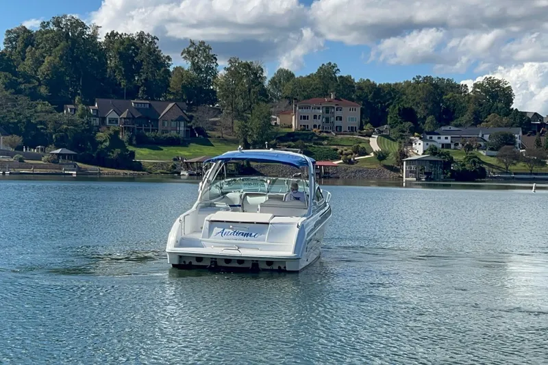 Slide: The Image of 2004 Formula 330 Sun Sport boat cruising on a scenic lake with waterfront homes. - 92