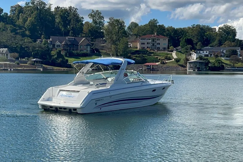 Slide: The Image of 2004 Formula 330 Sun Sport boat cruising on a serene lake with houses in the background. - 94