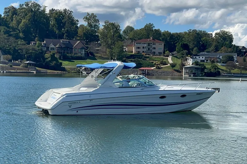 Slide: The Image of 2004 Formula 330 Sun Sport boat cruising on a serene lake with scenic background. - 98