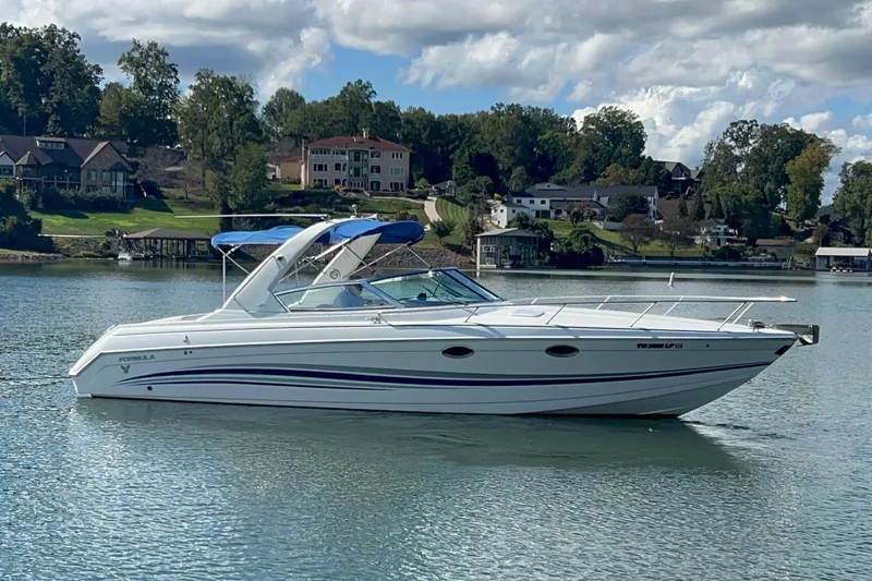 Slide: The Image of 2004 Formula 330 Sun Sport boat on a serene lake with houses in the background. - 99