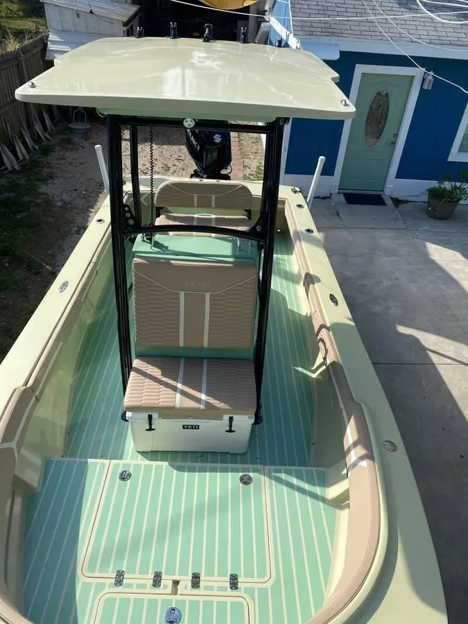 Slide: The Image of 2024 Exuma 22 EXTRA LITE boat with green and beige interior, docked near a blue house. - 4