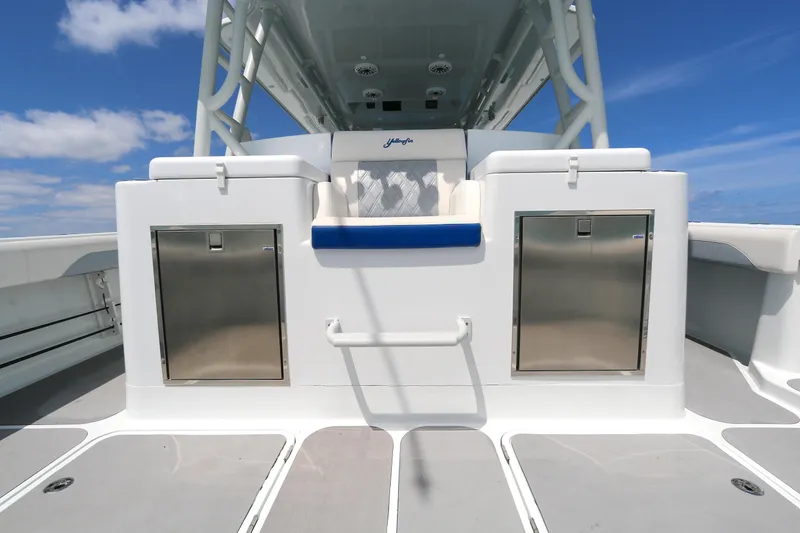 Slide: The Image of 2021 Yellowfin 54 Offshore boat deck with storage compartments and seating under a clear blue sky. - 4