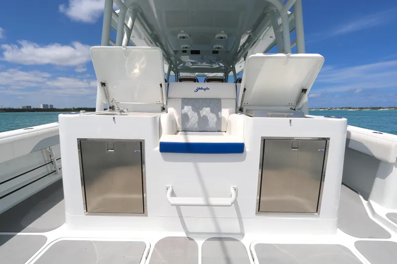 Slide: The Image of 2021 Yellowfin 54 Offshore boat deck with storage compartments and seating under a clear blue sky. - 5