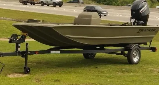 Slide: The Image of 2024 Tracker Grizzly 1648 SC boat on trailer, parked on grass near highway. - 2