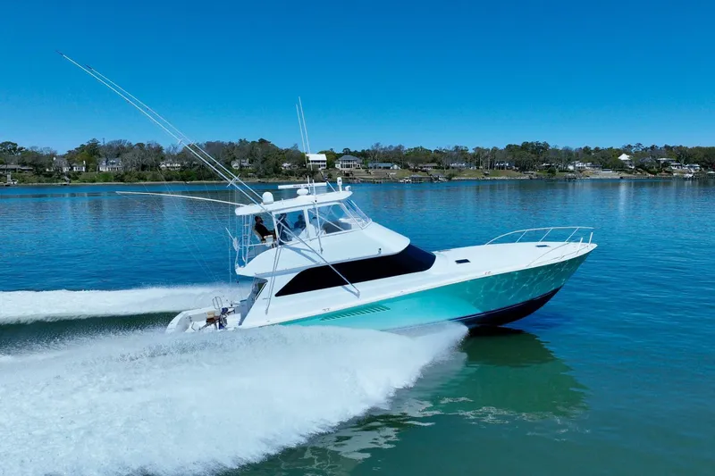 Slide: The Image of 2000 Viking 55 Convertible yacht cruising on a calm lake under clear blue skies. - 22