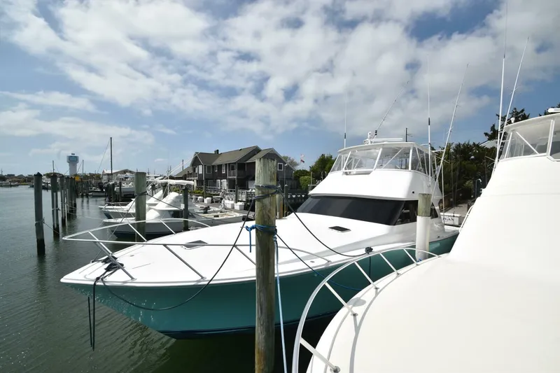 Slide: The Image of 2000 Viking 55 Convertible yacht docked at a marina under a partly cloudy sky. - 27