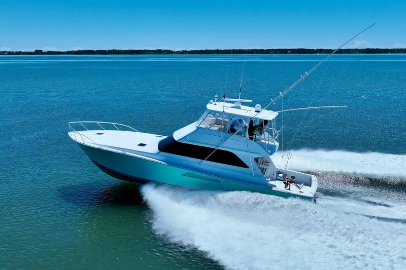 Slide: The Image of 2000 Viking 55 Convertible yacht cruising on open water under clear blue skies. - 5