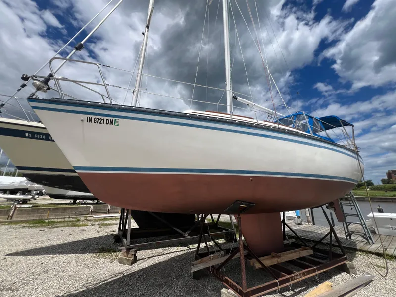 Slide: The Image of 1983 Hunter 27 sailboat on dry dock under cloudy sky. - 16