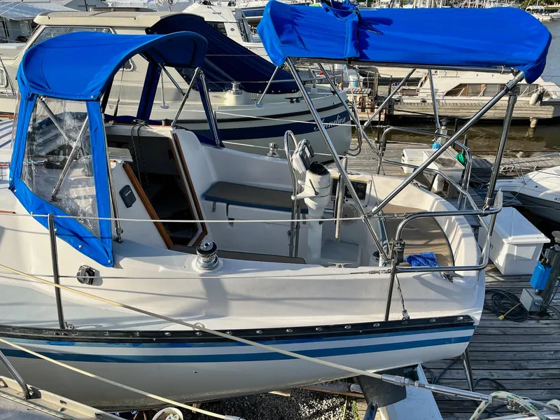 Slide: The Image of 1983 Hunter 27 sailboat with blue canopy docked at marina. - 2