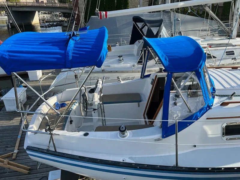 Slide: The Image of 1983 Hunter 27 sailboat with blue canopy docked at marina. - 3