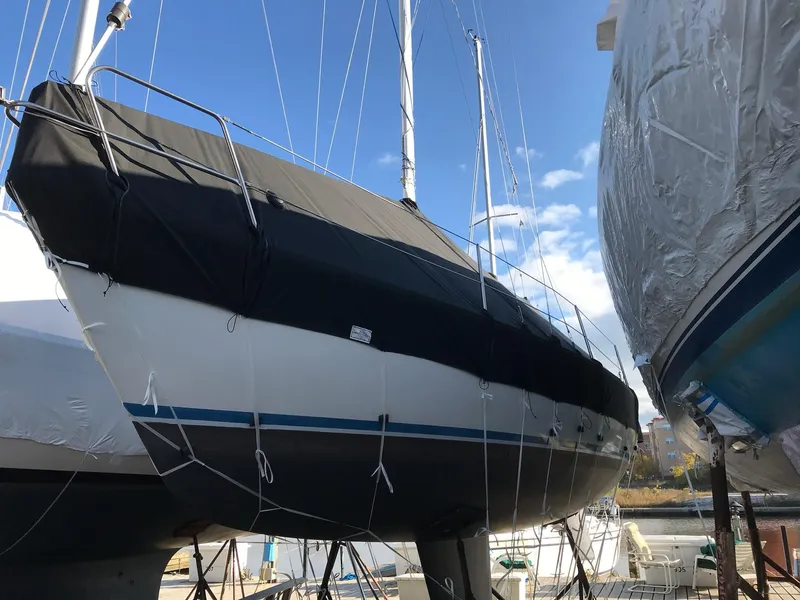 Slide: The Image of 1983 Hunter 27 sailboat in dry dock with black cover. - 33