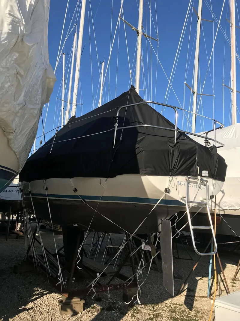 Slide: The Image of 1983 Hunter 27 sailboat covered and docked in a marina. - 34